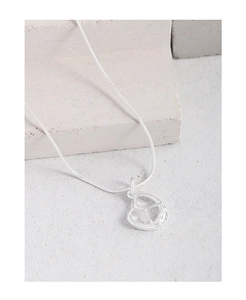 Minimalist silver hollow heart necklace on grey stone background detail shot