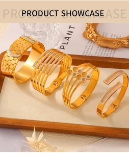 Detail of four gold-plated titanium steel bracelets with rhinestone accents on a wooden tray