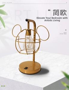 Close-up of golden Mickey-shaped metal wire desk lamp with warm LED Edison bulb