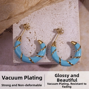 Macro shot of light blue enamel C-shaped hoop earrings with gold spiral thread detailing