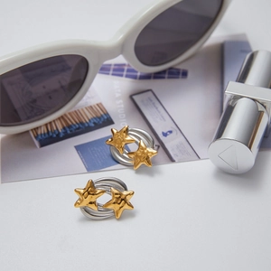Detailed view of gold star earrings on silver hoops with lifestyle accessories
