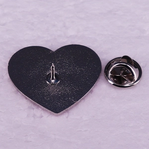 Rear view of silver metal heart pin badge with butterfly clutch on white texture