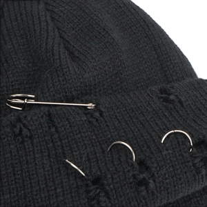 Detail of black knit beanie with punk silver metal pins and decorative rings texture