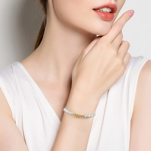 Gros plan d'un bracelet en argent S925 avec perles baroques et maillons dorés porté