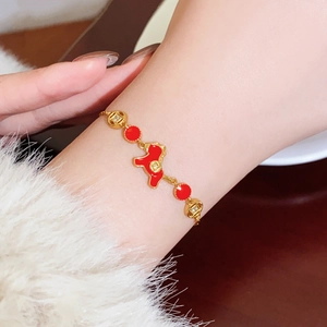 Detail of 18k gold plated horse charm bracelet on wrist with red enamel and crystals