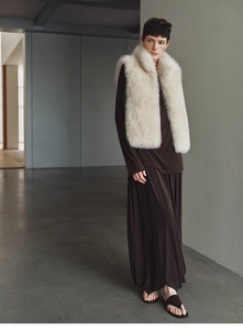 Close-up of off-white faux fox fur vest texture and plush collar detail