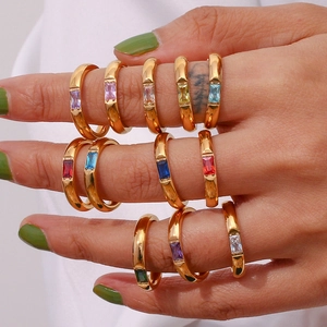 Detail of hand wearing stacked 18K gold plated rings with rectangular colorful zircons