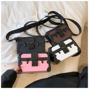 Macro shot showing four colorful box bags with metallic lock and stud details on white fabric