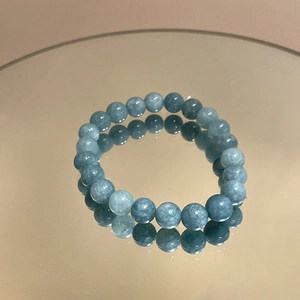 Detailed mirror view of light blue aquamarine beaded bracelet with floral camellia charm