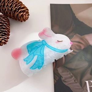 Close-up of cute white rabbit hair claw clip with blue bow detail on marble acrylic