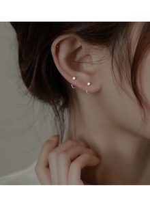 Close-up of minimalist silver hook earrings featuring a sparkling micro-set zircon stone