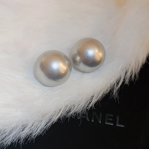 Detail view of large silver spherical stud earrings on luxury fur and black gift box