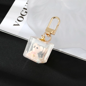 Macro detail of transparent resin cube pendant with pink bear and gold lobster clasp