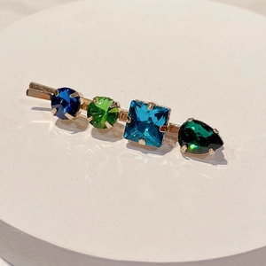 Close-up of golden hair clip with colorful square and drop-shaped crystal stones