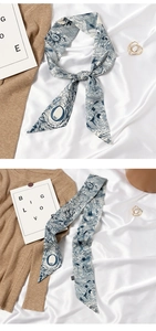 Detail of blue and white silk scarf tied in a knot and laid flat on fabric background