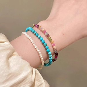 Detail of beaded bracelets with white shell, blue turquoise, and colorful crystals
