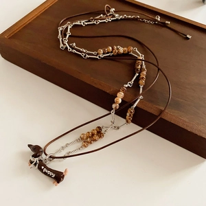 Detail of dachshund puppy pendant on a double-layer cord necklace over a wooden tray