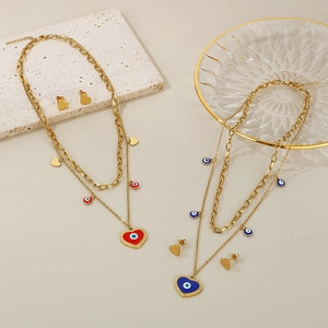 Detail of gold evil eye heart pendant necklaces and earrings on textured stones