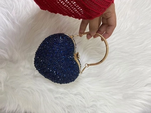 Detail of dark blue rhinestone heart-shaped evening bag with golden metal handle