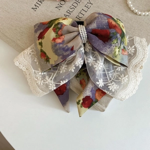 Macro detail of the acrylic lace bow hair claw featuring oil painting floral patterns