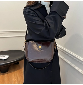Close-up of a vintage dark brown leather saddle bag with shiny gold hardware and flap buckle