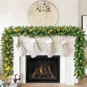 Close-up of a 9FT green Christmas garland with warm LED lights on a white fireplace
