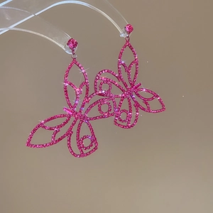 Macro detail of luxury sparkling hot pink butterfly earrings with zirconia diamonds