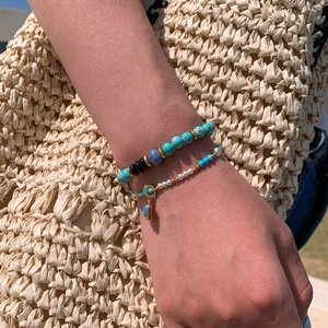 Close-up of turquoise beads and pearl layered bracelet set for summer beach style