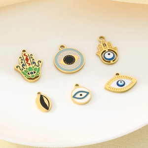 Macro shot of 18K gold plated Hamsa Hand and Evil Eye charms with colorful enamel details