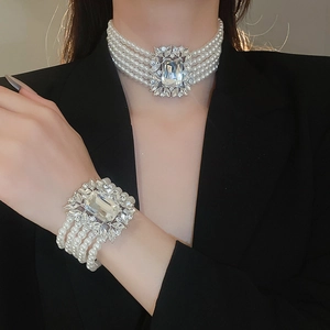 Close-up of layered pearl necklace and bracelet set with sparkling zircon insets