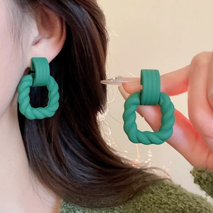 Detailed view of forest green geometric earrings with matte finish on female model