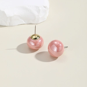 Detail of elegant pink faux pearl stud earrings with golden metallic caps on top
