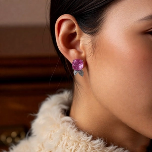 Macro detail of ice rose flower earring with pink gemstone and silver leaf design