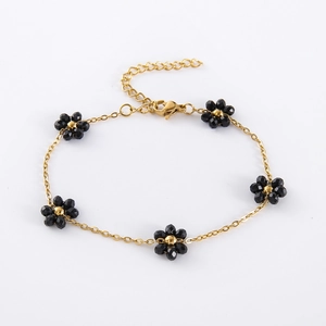 Close-up of golden link bracelet featuring six handmade black beaded flower charms