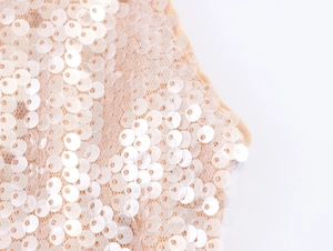 Gros plan sur les paillettes champagne et la maille transparente d'une robe de soirée