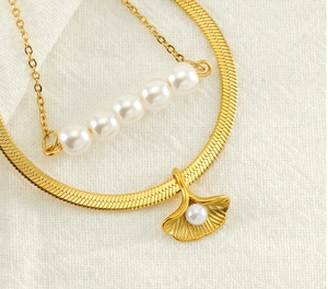 Detail of double-layer gold necklace with ginkgo leaf pendant and elegant white pearls