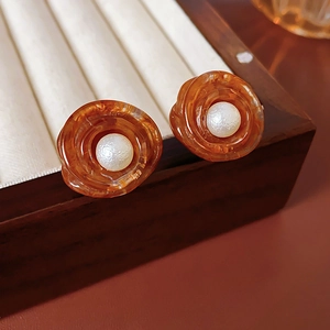 Macro shot of retro flower earrings with amber resin petals and a pearl center
