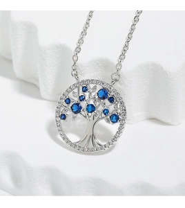 Macro shot of silver tree of life necklace with blue zircons on white stone texture