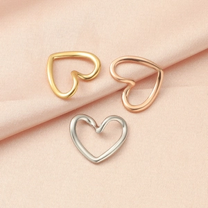 Polished hollow heart charms in gold, rose gold, and silver on silk fabric