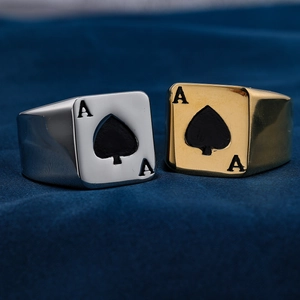 Macro view of gold and silver Ace of Spades biker rings on textured blue fabric