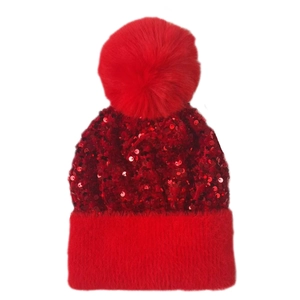 Close-up of red sequined knit hat with fluffy pompom and plush velvet faux fur trim