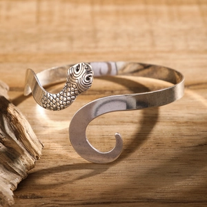 Vintage silver snake arm cuff with textured serpent head on rustic wood background