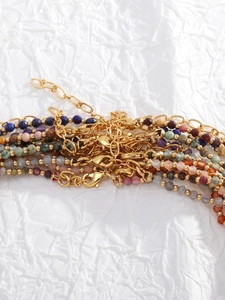 Close-up of colorful natural stone beaded necklaces with gold lobster clasps and chains
