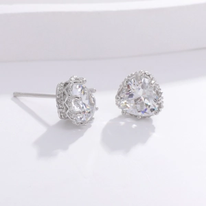 Macro shot of silver heart-shaped stud earrings with sparkling cubic zirconia on stone