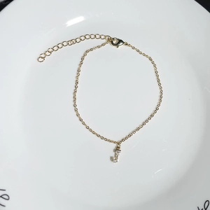 Close-up of gold chain bracelet with sparkling zircon capital J initial pendant