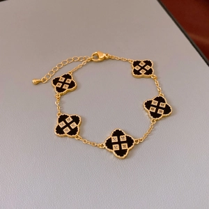 Close-up of gold plated bracelet with black clover charms and clear zircon stones