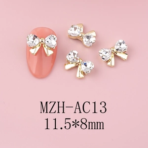 Detailed view of golden metal bow nail charms with rhinestones sized 11.5x8mm