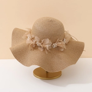 Détail d'un chapeau de paille avec fleur en gaze délicate et ornements de perles
