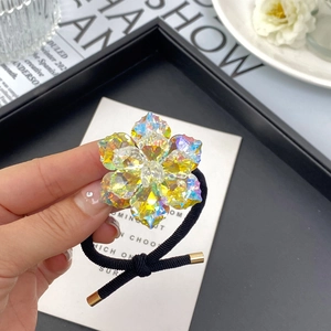 Detailed view of a dual-layer yellow crystal flower hair tie with a black elastic band