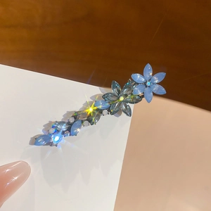 Vue rapprochée d'une pince à cheveux fleur en cristal bleu avec perles sur métal argenté